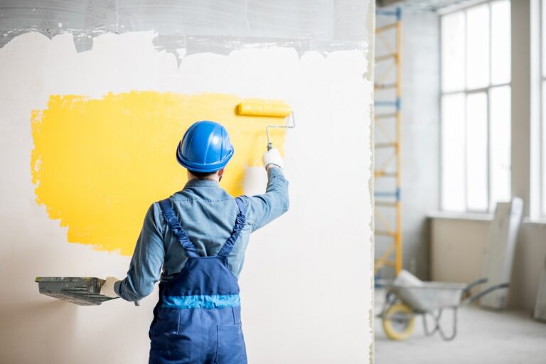 Workamn painting wall indoors